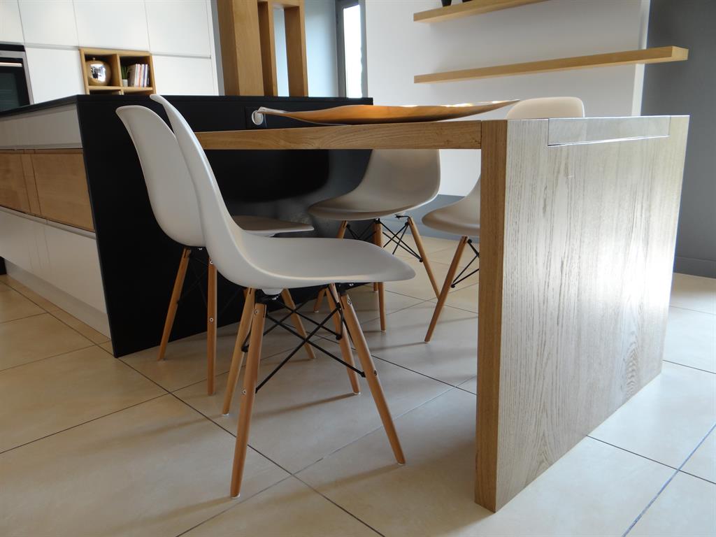 La table de cuisine en bois clair prolonge l'îlot central
